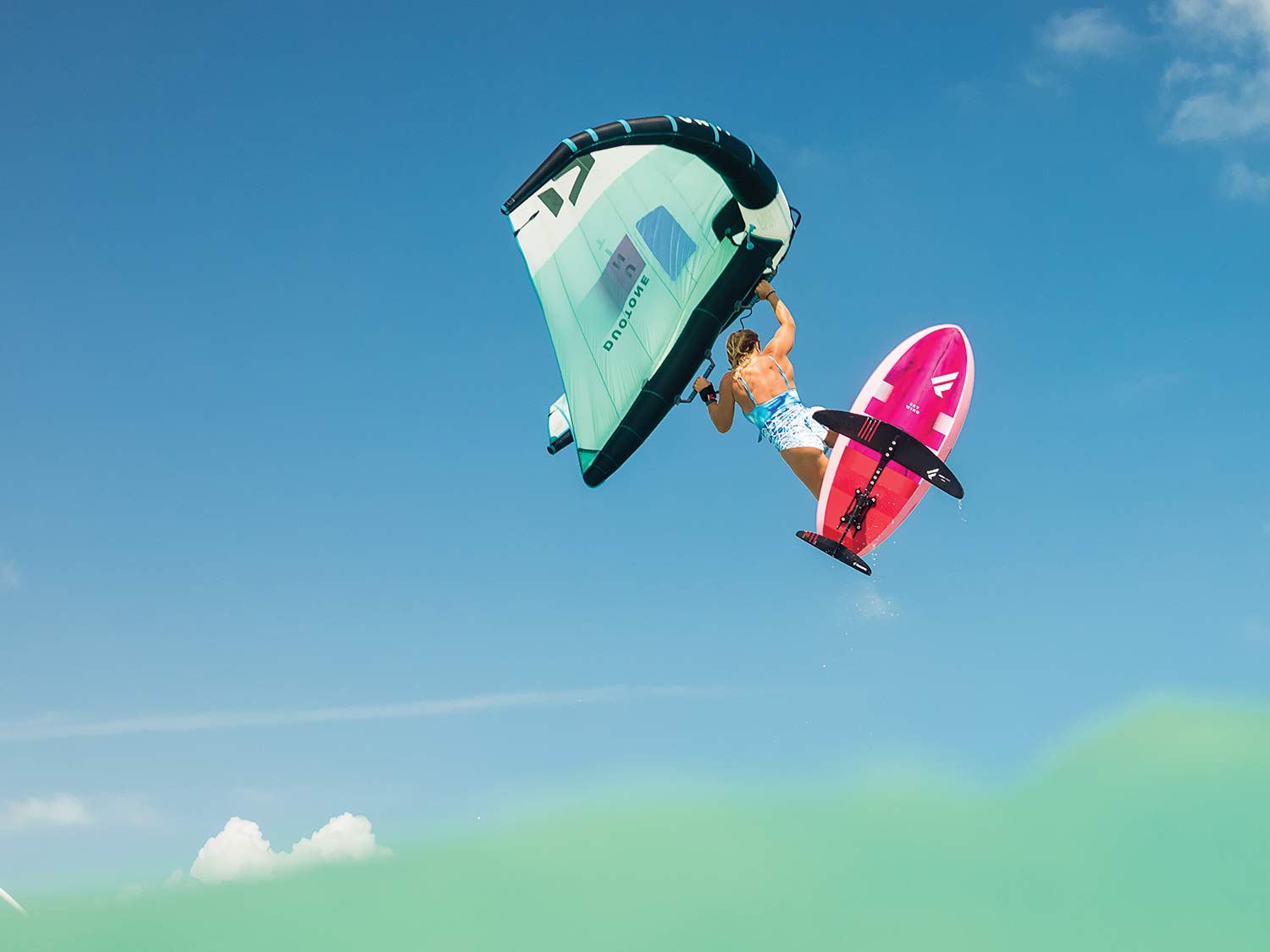 A woman freestyle kiteboarding through the air.
